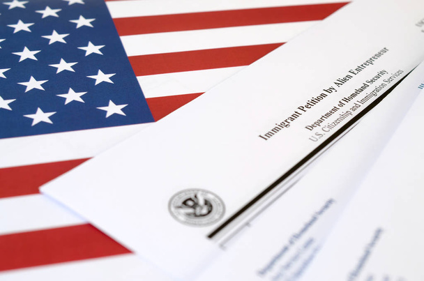 I-526 Petycja Imigrant przez cudzoziemca przedsiębiorca pusty formularz leży na fladze Stanów Zjednoczonych z kopertą z Departamentu Bezpieczeństwa Wewnętrznego - Zdjęcie, obraz