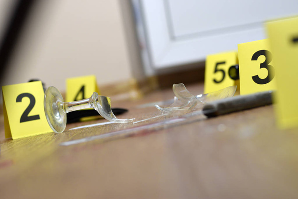Расследование места преступления - нумерация улик после убийства в квартире. Разбитый бокал вина, ножа и бутылки в качестве доказательства
 - Фото, изображение