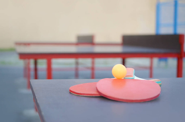 rakiety i piłka na stół do ping ponga w odkrytym boisku sportowym. Koncepcja aktywnego sportu i treningu fizycznego - Zdjęcie, obraz