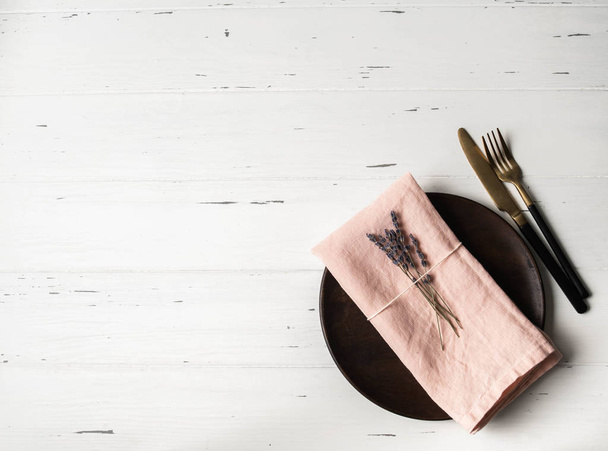 Rustikální prostírání stolu s talířem, růžovým ubrouskem, levandulí a spotřebiči na bílém dřevěném stole. Horní pohled. - Fotografie, Obrázek