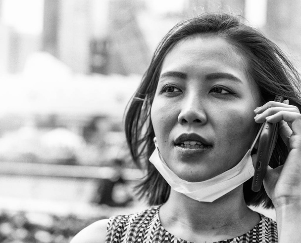 Молода азіатка з мобільним телефоном і проти забруднення повітряної маски захист від хвороб і хвороб
. - Фото, зображення