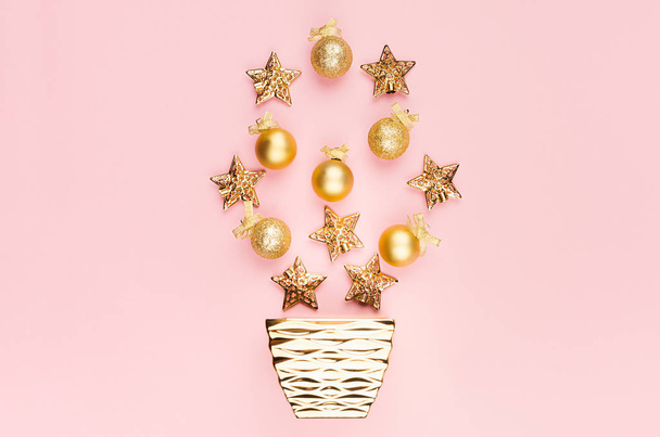 New Year modern stylish background in gold and pink color - golden stars, glittering balls, ribbon, bowl on pastel pink color, top view, copy space. - Φωτογραφία, εικόνα