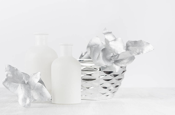 Blank white bottles for cosmetic as mock up for advertising, design, branding identity decorated silver leaves, bowl on soft light white table. - Фото, изображение