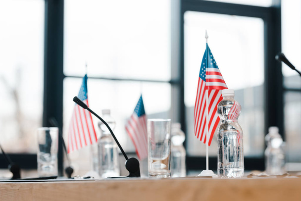 selective focus of american flags near glasses and bottles with water on table  - Foto, imagen