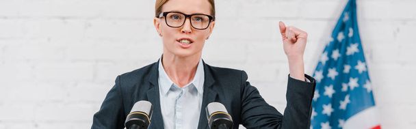 panoramic shot of attractive speaker in glasses gesturing while talking near microphones  - Photo, Image