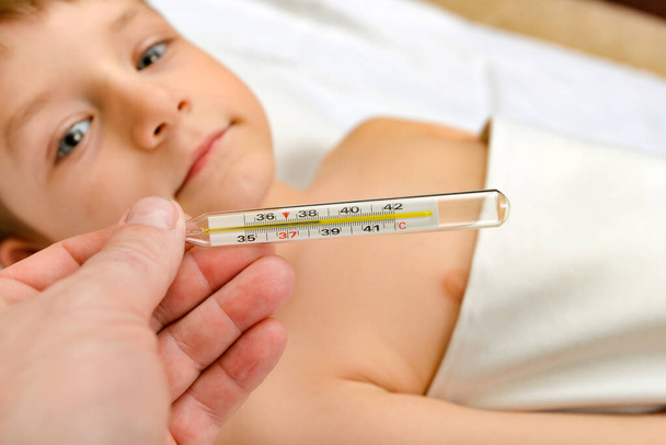 der Arzt zeigt eine hohe Temperatur auf dem Thermometer eines kalten Kindes - Foto, Bild