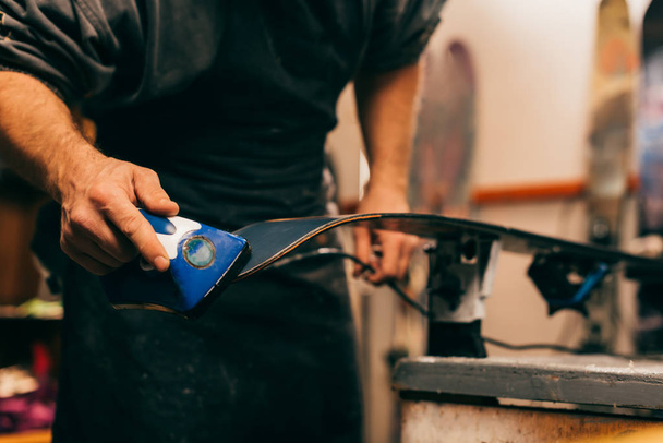 cropped view of worker using wax iron on ski in repair shop  - Zdjęcie, obraz