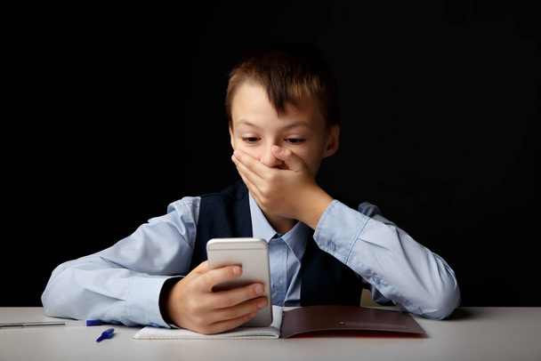 Cyberbullying concept. Stressed and upset school boy with gadget isolated. - Photo, Image