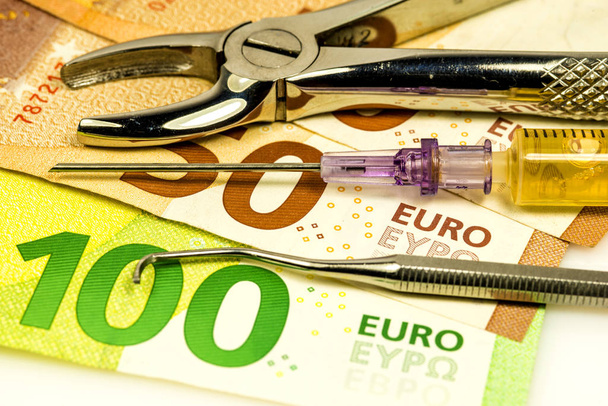 fórceps dentários e injeção com notas de euro
 - Foto, Imagem