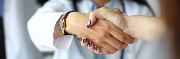 Arm of female GP shaking hands with visitor - 写真・画像