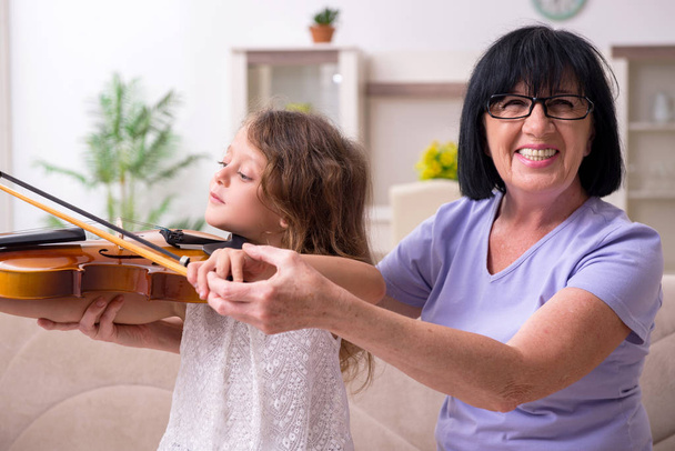 Oude dame leert klein meisje viool te spelen - Foto, afbeelding