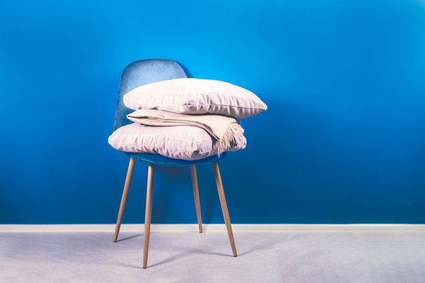 Moderna silla de terciopelo azul con cojines beige y tiro
 - Foto, Imagen
