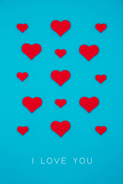 Greeting holiday card made of red hearts over blue background. - Photo, Image