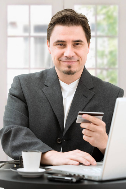 portrait of a smiling businessman sitting at the table with laptop and coffee - Фото, зображення