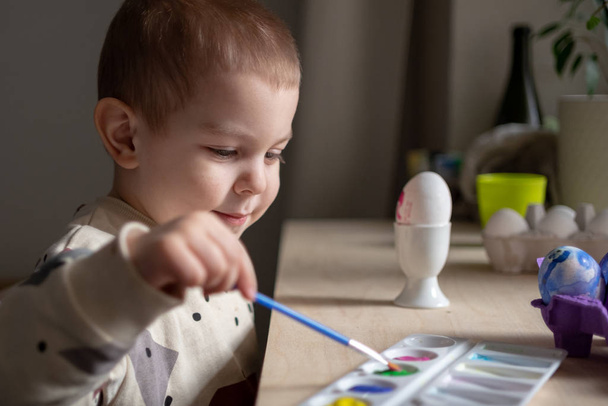 Toddler boy painting easter eggs preparing for holidays. Easter tradition  - Foto, imagen