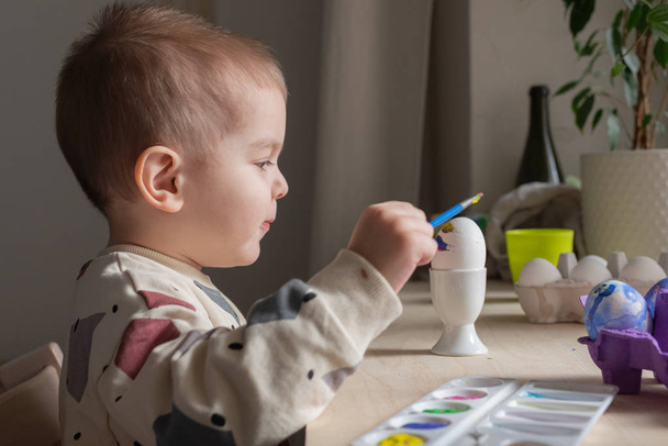 Toddler boy painting easter eggs preparing for holidays. Easter tradition  - Photo, image