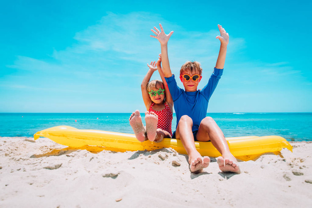 happy cute boy and girl with floatie on beach vacation - Foto, imagen