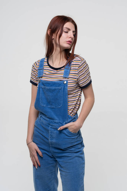 young beautiful girl is standing in blue overalls - Photo, Image