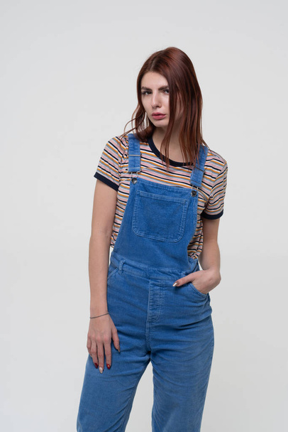 young beautiful girl is standing in blue overalls - Fotografie, Obrázek