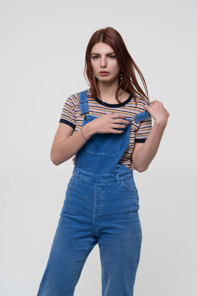 young beautiful girl is standing in blue overalls - Фото, зображення