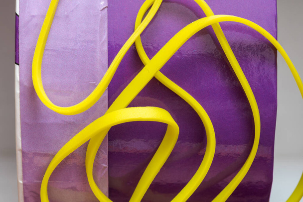 kasa keltaisia pieniä kuminauhoja eristetty violetti takana maahan
 - Valokuva, kuva
