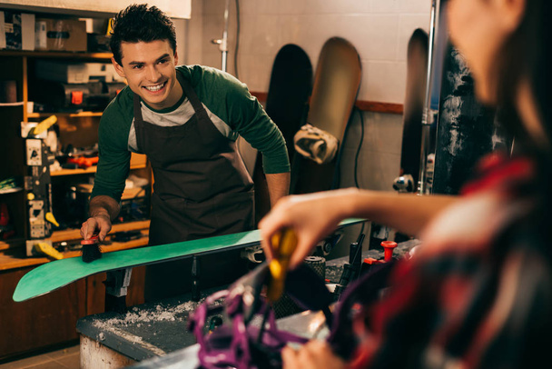 valikoiva painopiste hymyilevä työntekijä puhdistus hiihto harjalla ja kollega taustalla
  - Valokuva, kuva