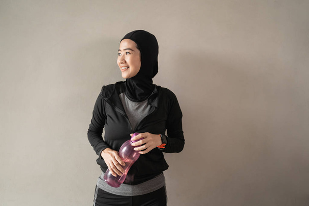 hijab sporty asian ladies wearing sportswear hold a bottle - Фото, изображение