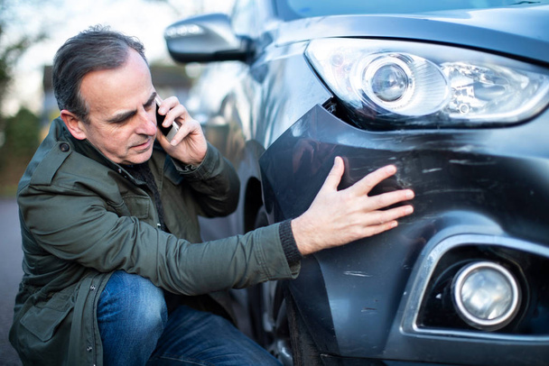 Unhappy Mature  Male Driver With Damaged Car After Accident Call - 写真・画像