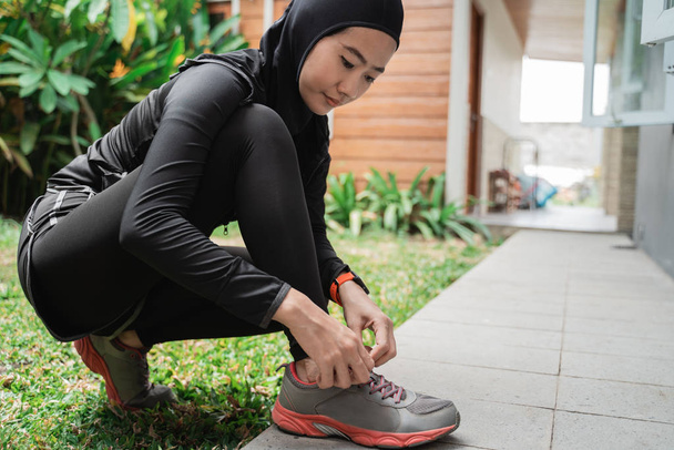 Young asian muslim women wear sports hijabs and fix shoelaces before jogging - Zdjęcie, obraz