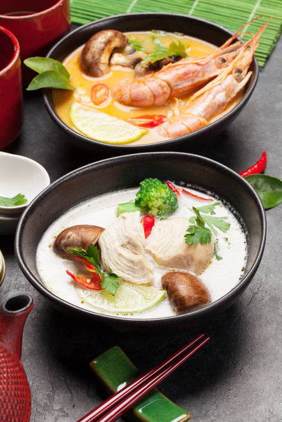 Soupes thaïlandaises traditionnelles Tom Yum et Tom Kha avec fruits de mer, poulet, champignons, lait de coco et épices chaudes. Avec pot à thé vert et bol
 - Photo, image
