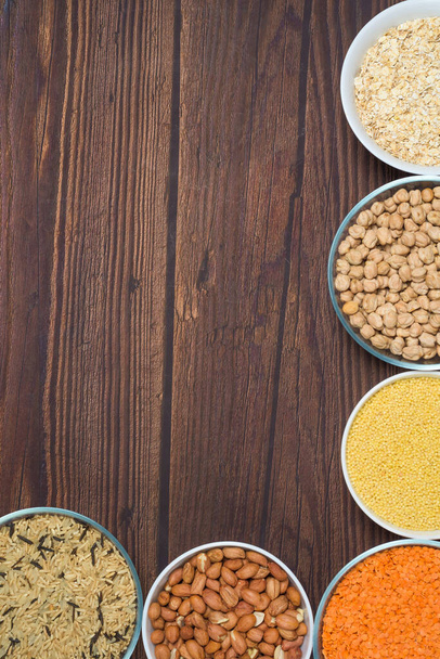 grains red lentils, basmati rice, buckwheat, chickpeas, millet in plates. organic healthy cereals. on a wooden background. natural vegetarian vegetable protein . the view from the top. vertical frame - Photo, image