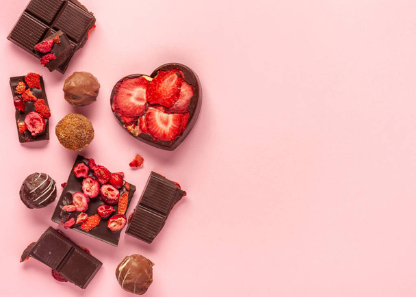 Different types of chocolate sweets with dried berries. Pink background - Foto, afbeelding