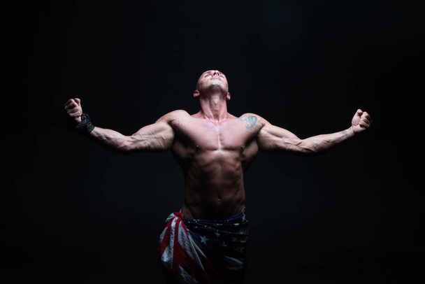 Атлетичный культурист-мужчина на тёмном фоне. Человек с красивым body.athletics, упражнения, здоровье, власть, сила, человек
, - Фото, изображение