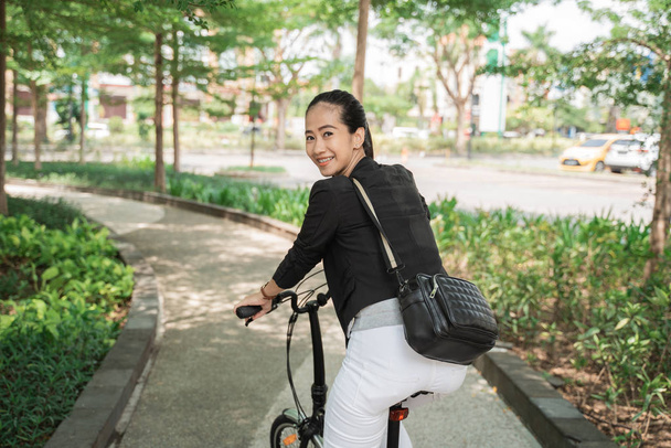 Smiling business woman riding her folding bike - Фото, изображение