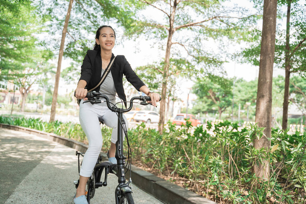 笑顔ビジネス女性に乗る彼女の折りたたみ自転車 - 写真・画像