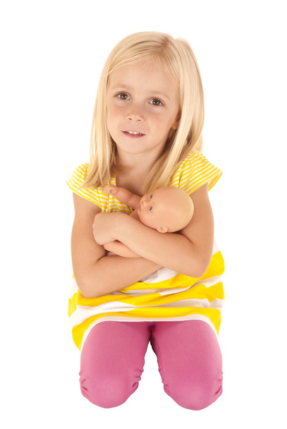 young female child holding a baby doll kneeling down - Фото, зображення