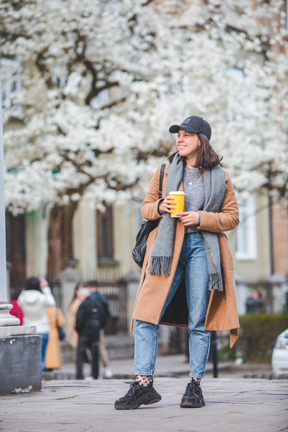 jonge stijlvolle vrouw lopen door straat met koffiekop - Foto, afbeelding