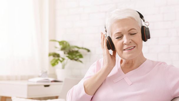 Χαλαρή ηλικιωμένη κυρία που απολαμβάνει τον υπέροχο ήχο των νέων ακουστικών - Φωτογραφία, εικόνα