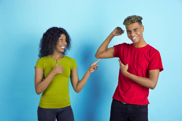 Молодой эмоциональный афро-американец мужчина и женщина на синем фоне
 - Фото, изображение