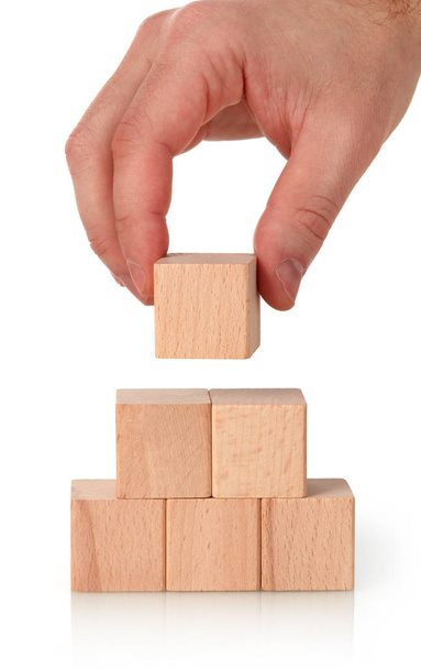 Бизнесмен строит пирамиду из деревянных блоков
 - Фото, изображение