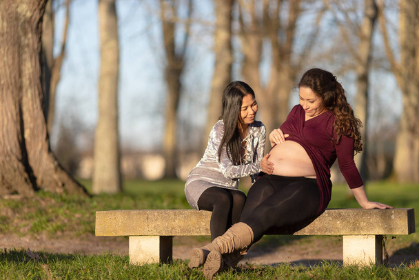 Νεαρή έγκυος γυναίκα που επιδεικνύει το μωρό της - Φωτογραφία, εικόνα