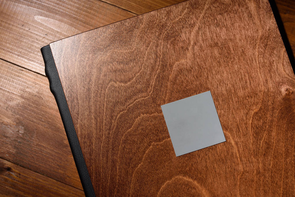 Φωτογραφικό βιβλίο σε ξύλινο κάλυμμα σε ξύλινο τραπέζι. Σκληρό φως - Φωτογραφία, εικόνα