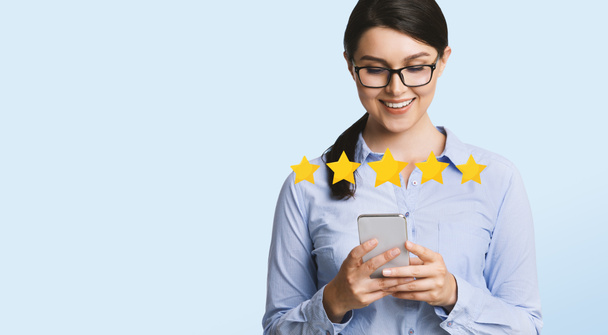 zufriedene Geschäftsfrau bewertet mobile Anwendung auf Smartphone mit fünf Sternen - Foto, Bild
