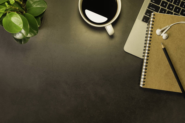 Вид сверху на рабочий стол, лампа Light, черный тёмный верхний стол с ноутбуком, наушниками, карандашом и белой чашкой черного кофе. Квартира с копировальным пространством
. - Фото, изображение