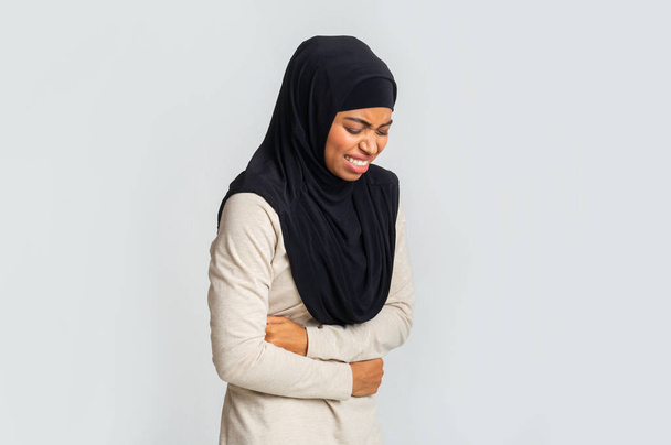 Black muslim girl in hijab suffering from abdominal pain - Photo, Image
