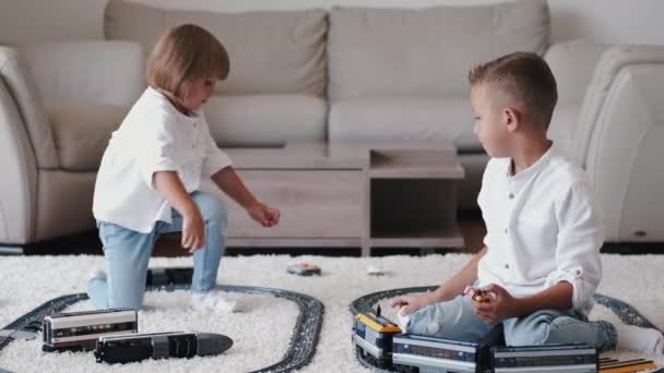 Dwoje dzieci bawiących się koleją zabawek w domu - Materiał filmowy, wideo