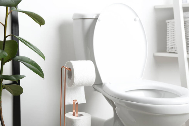 Holder with paper rolls near toilet bowl in bathroom - Foto, afbeelding