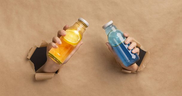 Mani attraverso cartone contenente bottiglie di disintossicazione gialle e blu
 - Foto, immagini