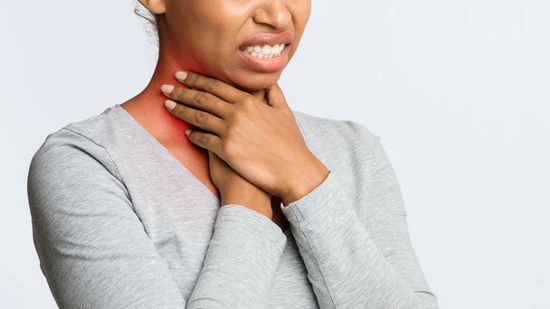 Kasvatettu musta nainen pitelee hänen tulehtunut kurkku
 - Valokuva, kuva
