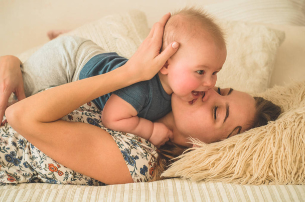 Amour et famille. Portrait d'un bébé garçon avec sa mère sur le lit. Maman joue et embrasse son enfant
 - Photo, image